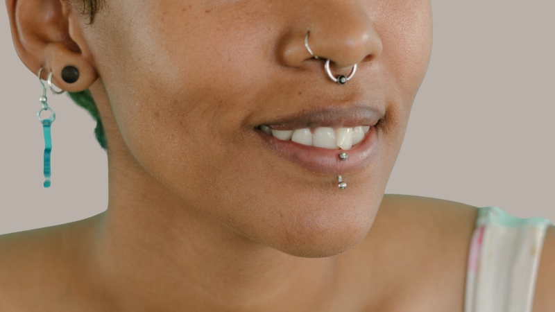 Woman smiling with a labret lip piercing and multiple facial piercings