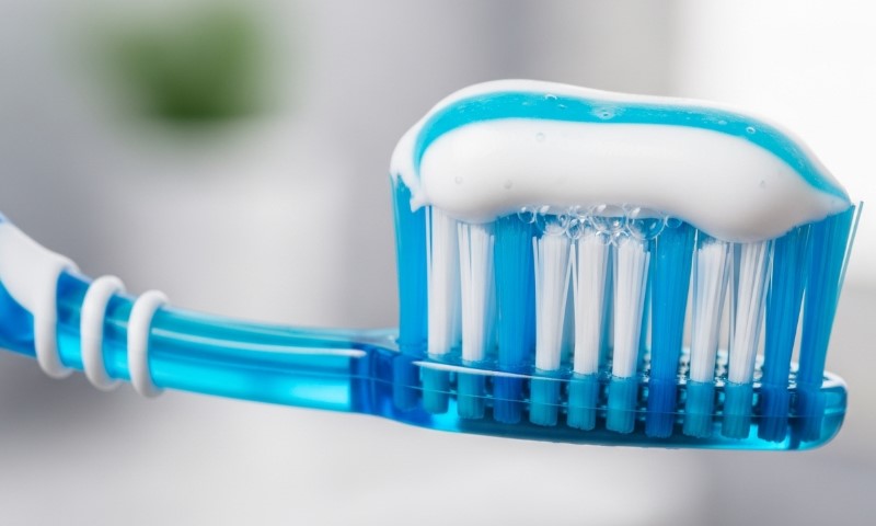 A blue toothbrush with white toothpaste applied to the bristles