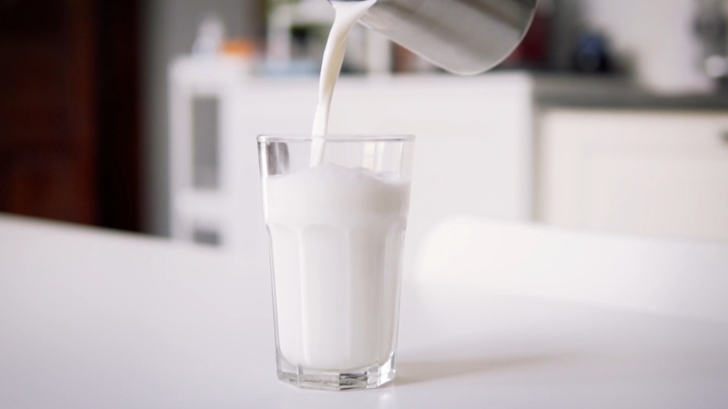 Milk poured into a clear glass on a kitchen counter