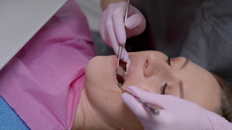 A patient lies in a dental chair as a dentist examines a wisdom tooth area with instruments
