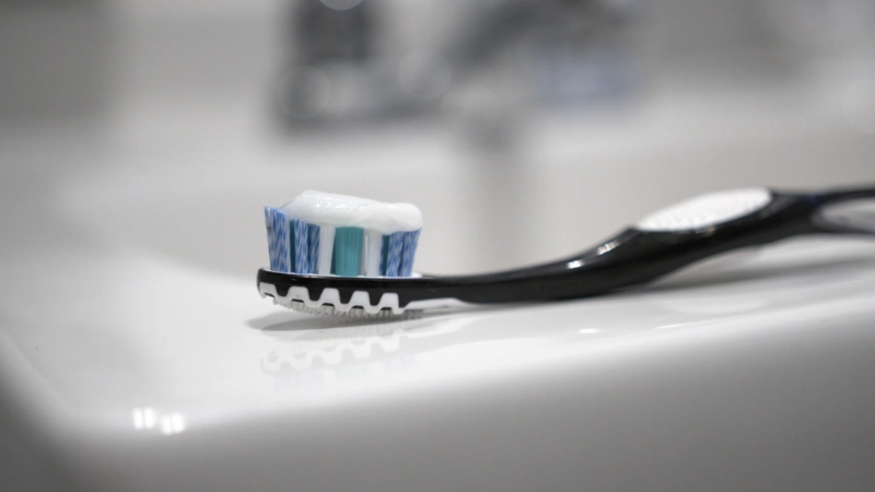 A foamy toothbrush rests on a sink and highlights oral bacterial growth on a toothbrush