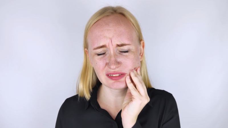 A woman presses her jaw with clear wisdom tooth pain on her face