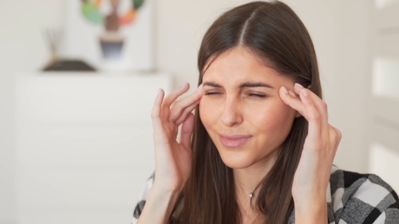 A woman presses her temples as she deals with a strong headache